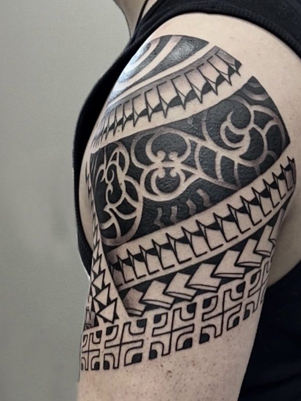 Geometrisches Tribal-Tattoo auf Schulter und Oberarm